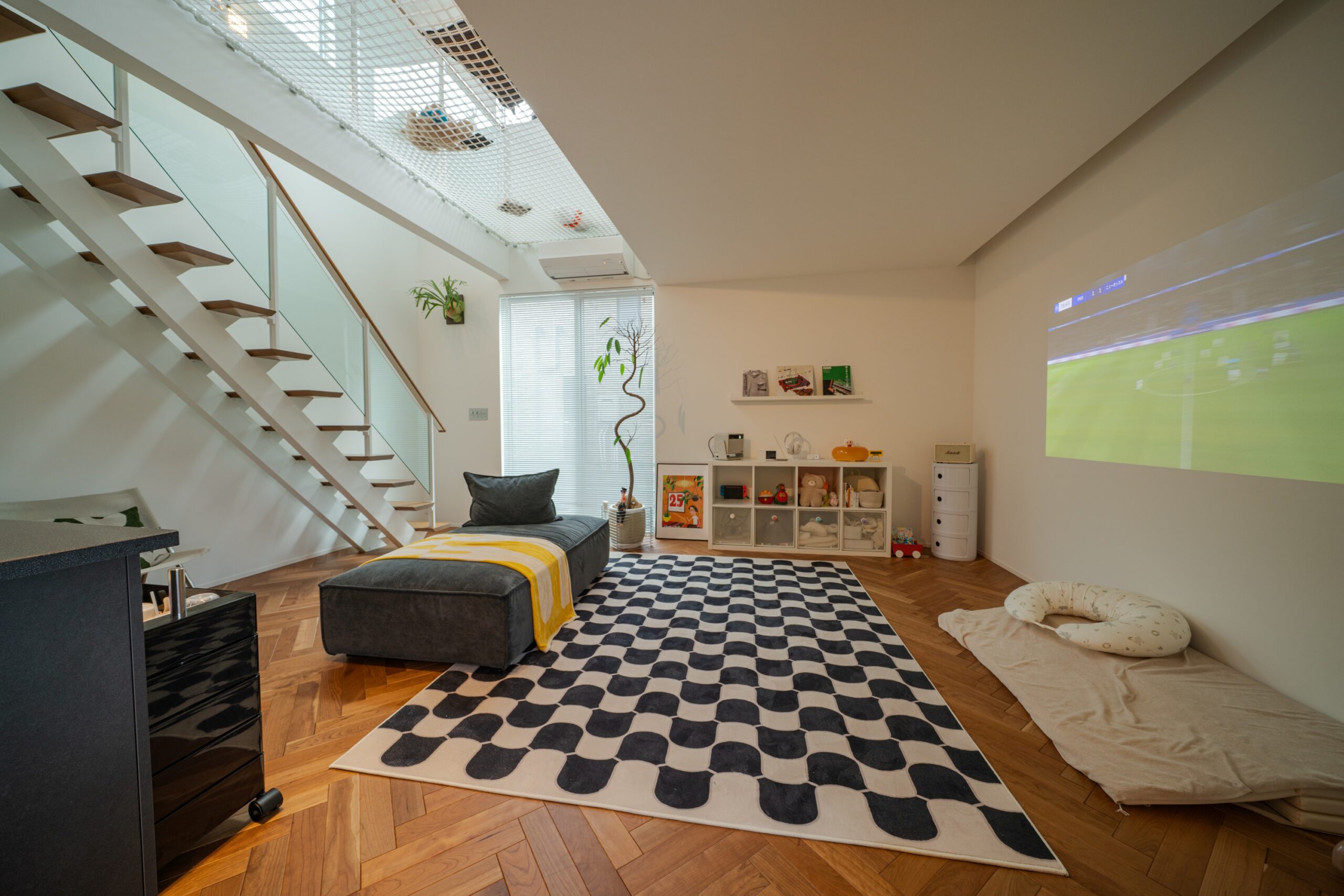 白壁をスクリーンとして活用し、プロジェクターでスポーツ観戦などを大画面で楽しめるリビング設計です 。