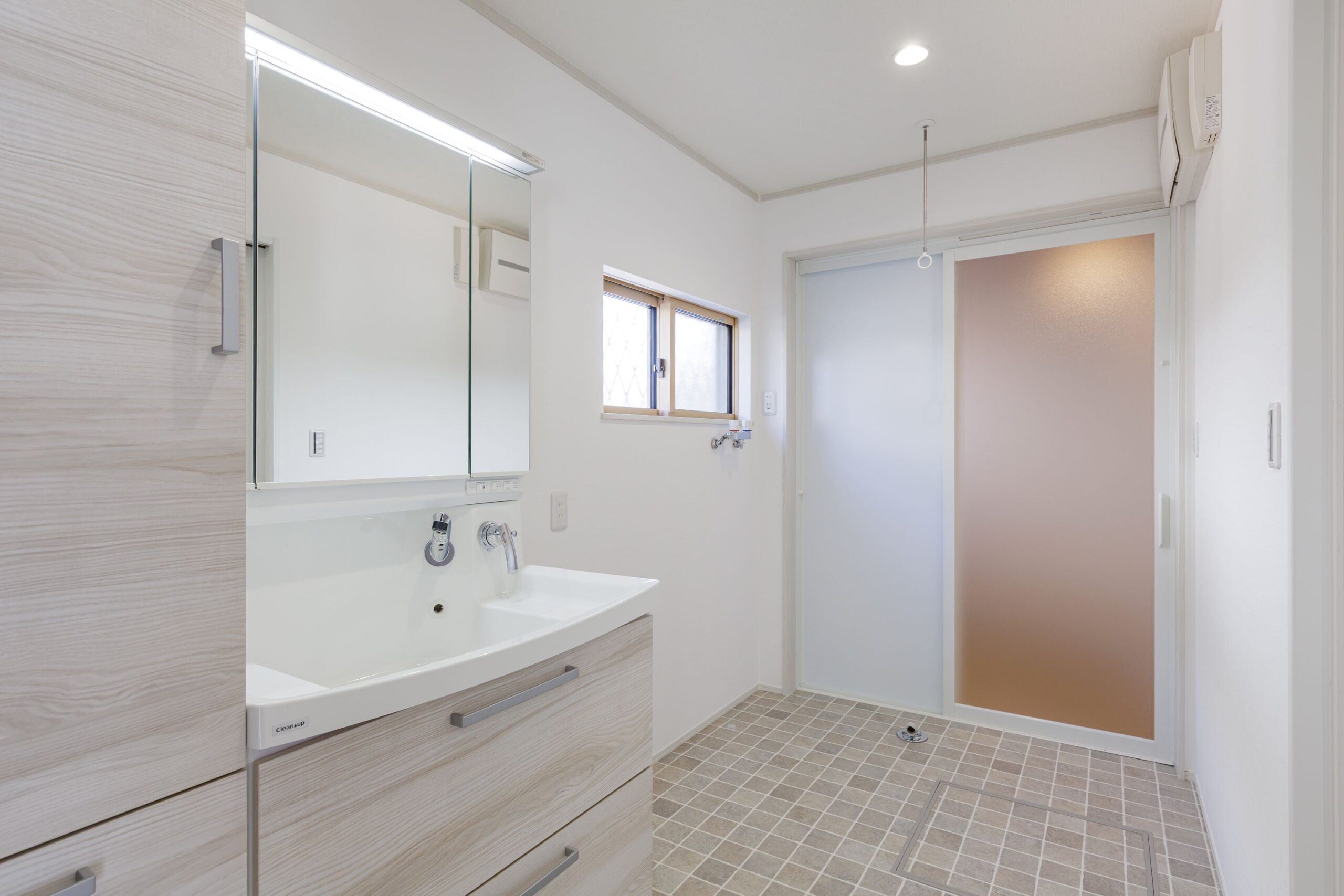 お手入れのしやすいタイル調のクッションフロアを採用した洗面室。室内物干し(ホスクリーン)を設置し、共働き世帯に嬉しい「家事ラク」仕様に。白を基調とした清潔感のある空間です。