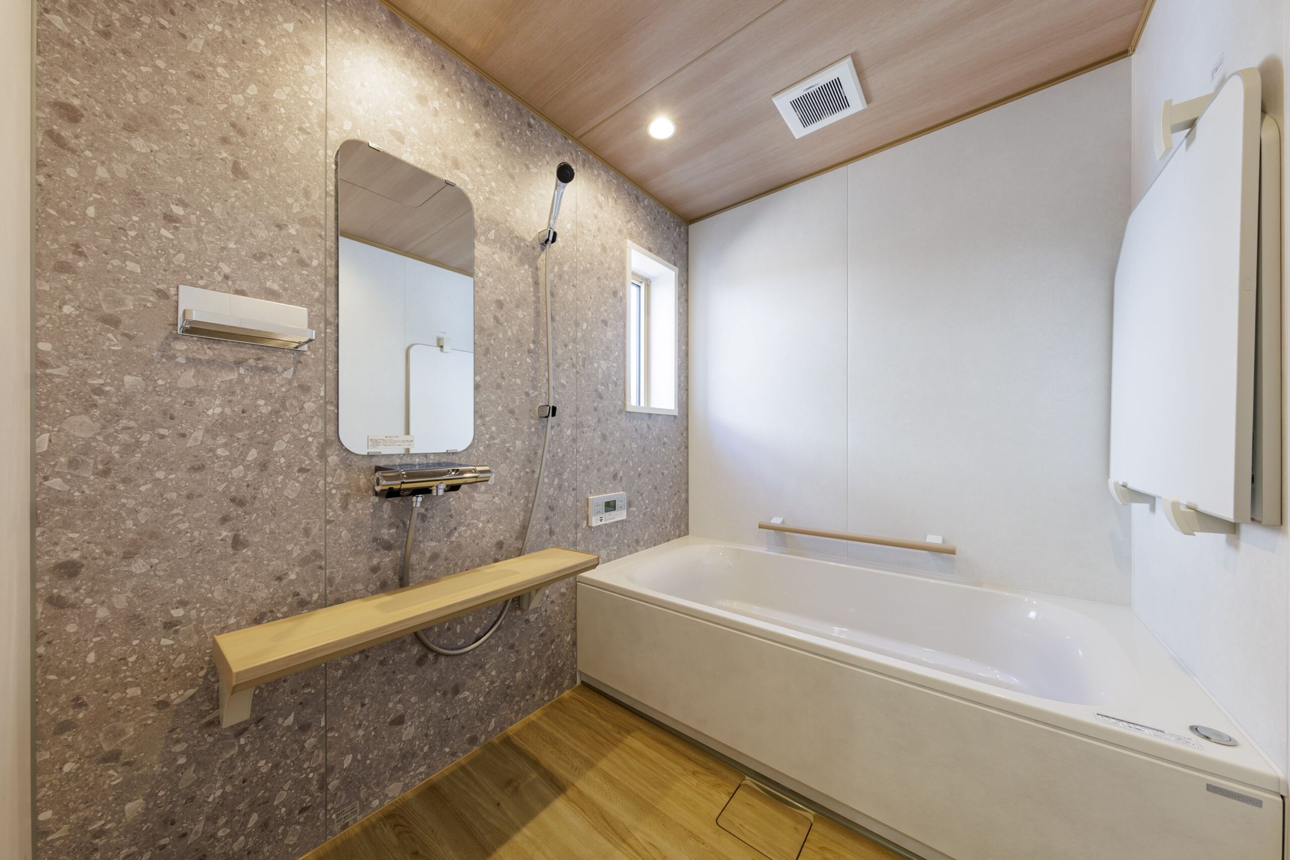 落ち着いた石目調のアセントパネルと、温かみのある木目調の天井を組み合わせたバスルーム。ゆったりとした浴槽で、贅沢なリラックスタイムを過ごせます。