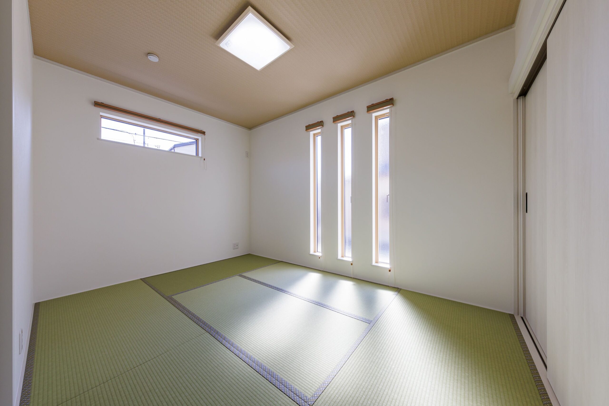 3本の縦長スリット窓が印象的な和室。モダンな印象を与えつつ、お昼寝やゲストルームとしても多目的に使える空間です。壁紙と天井のコントラストが、落ち着いた和の雰囲気を引き立てます。