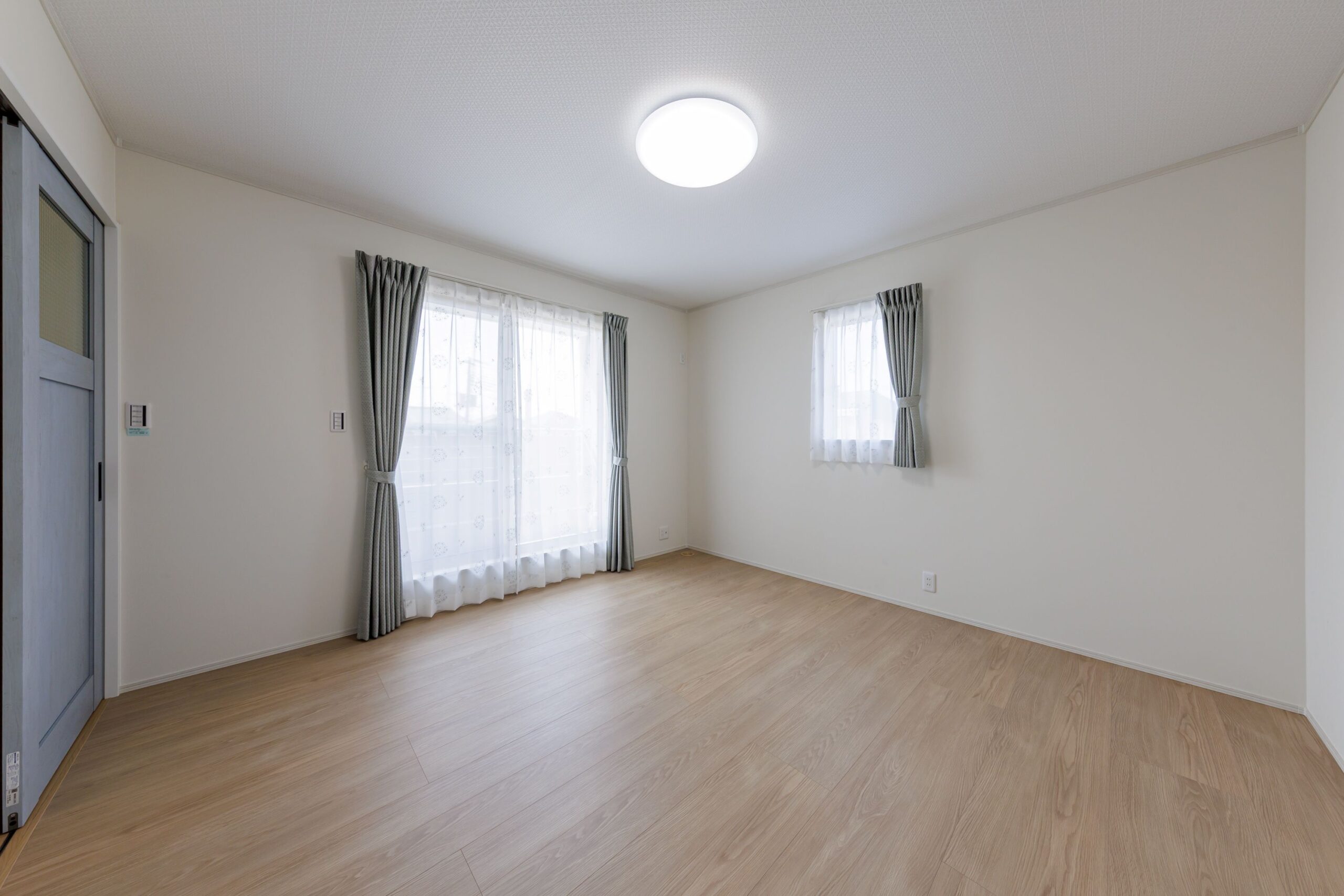 淡いブルーのドアがアクセントになった洋室。2面採光を確保し、風通しも抜群です。どんなインテリアにも馴染むシンプルなデザインで、家族の成長に合わせてフレキシブルに使えます。